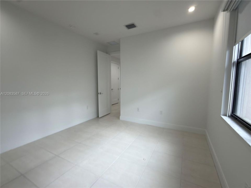 Neutral-toned ceramic tile flooring, recessed ceiling lighting, and crisp white interior walls with solid-core doors