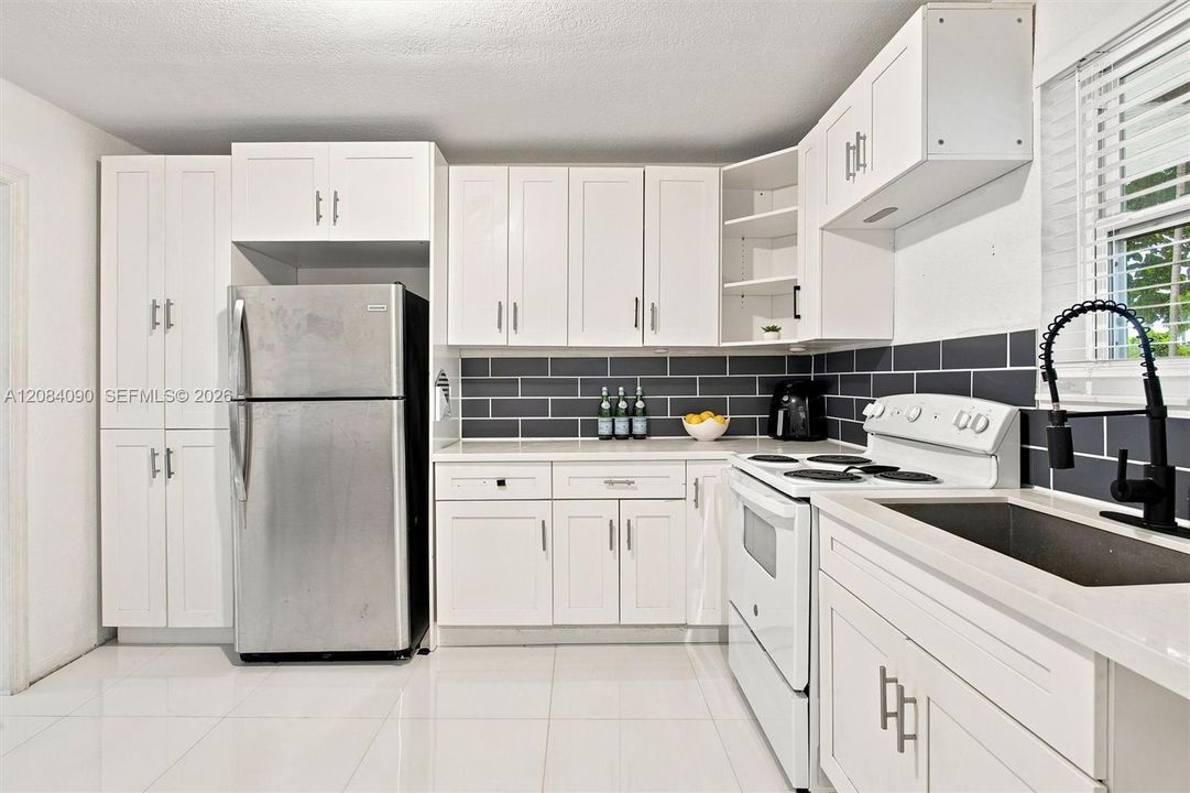 Bright, updated kitchen with white cabinetry, generous counter space, modern subway-tile backsplash, ample storage, and abundant natural light.