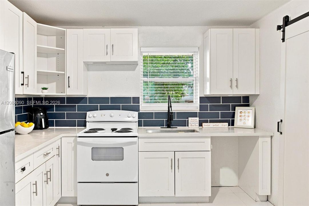 Bright, updated kitchen with white cabinetry, generous counter space, modern subway-tile backsplash, ample storage, and abundant natural light.