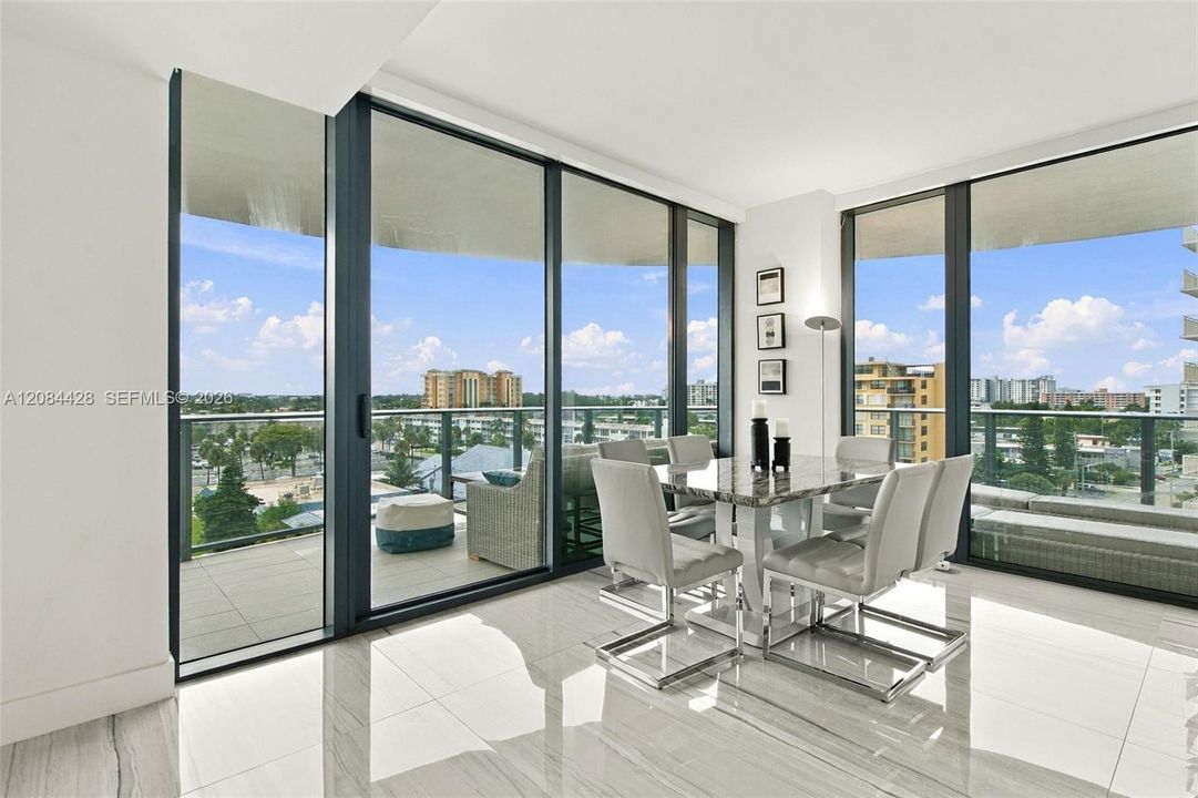 Bright dining area surrounded by floor-to-ceiling windows with direct balcony access.