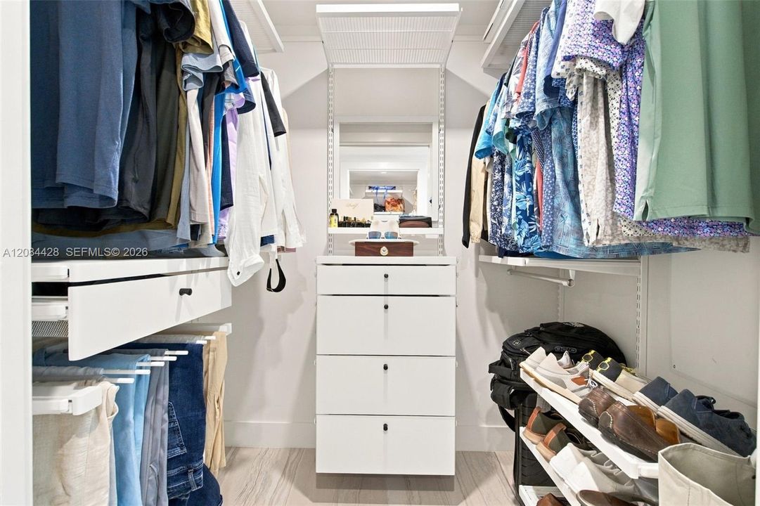 First of two separate custom-fitted walk-in closets with built-in drawers and hanging storage. Closets will be cleared for tenant use.