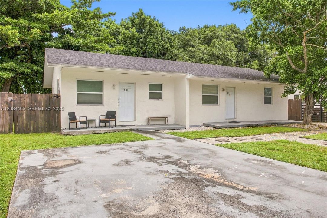 Well-maintained duplex with a clean, inviting exterior, gated parking, and a spacious driveway. Mature trees and surrounding greenery add shade and curb appeal, while the fenced outdoor area provides added privacy and convenience.