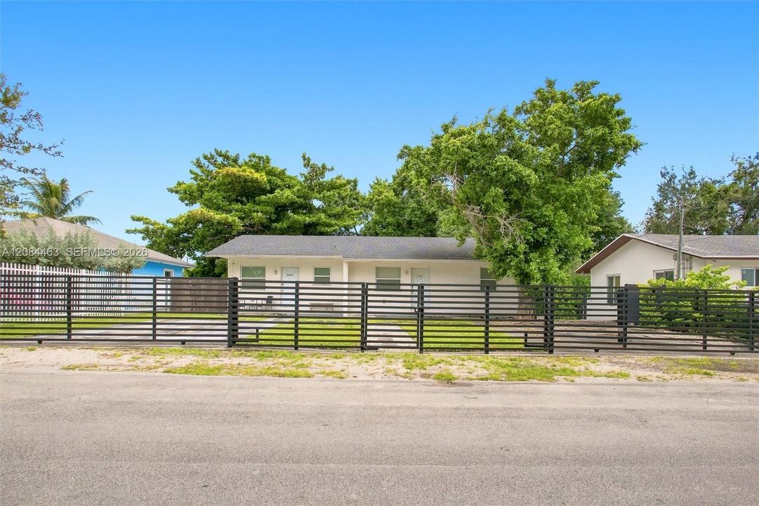 Well-maintained duplex with a clean, inviting exterior, gated parking, and a spacious driveway. Mature trees and surrounding greenery add shade and curb appeal, while the fenced outdoor area provides added privacy and convenience.