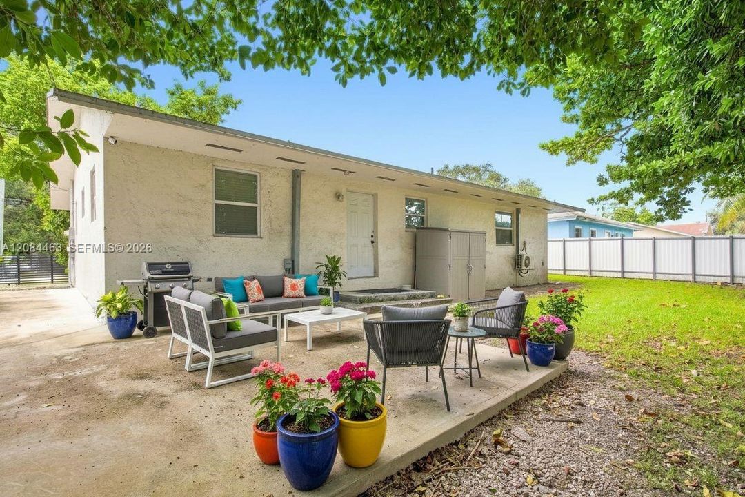 Spacious private backyard with a patio area perfect for relaxing or entertaining, surrounded by mature trees and a fenced yard for added privacy. *Photo virtually staged.*