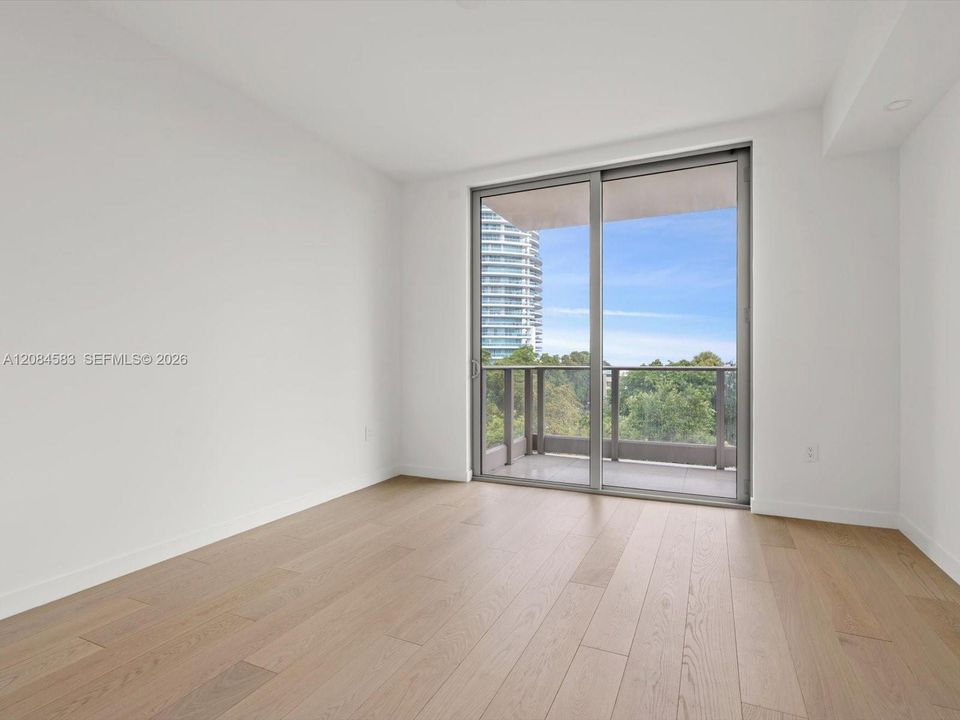 Primary bedroom with floor-to-ceiling glass and balcony access