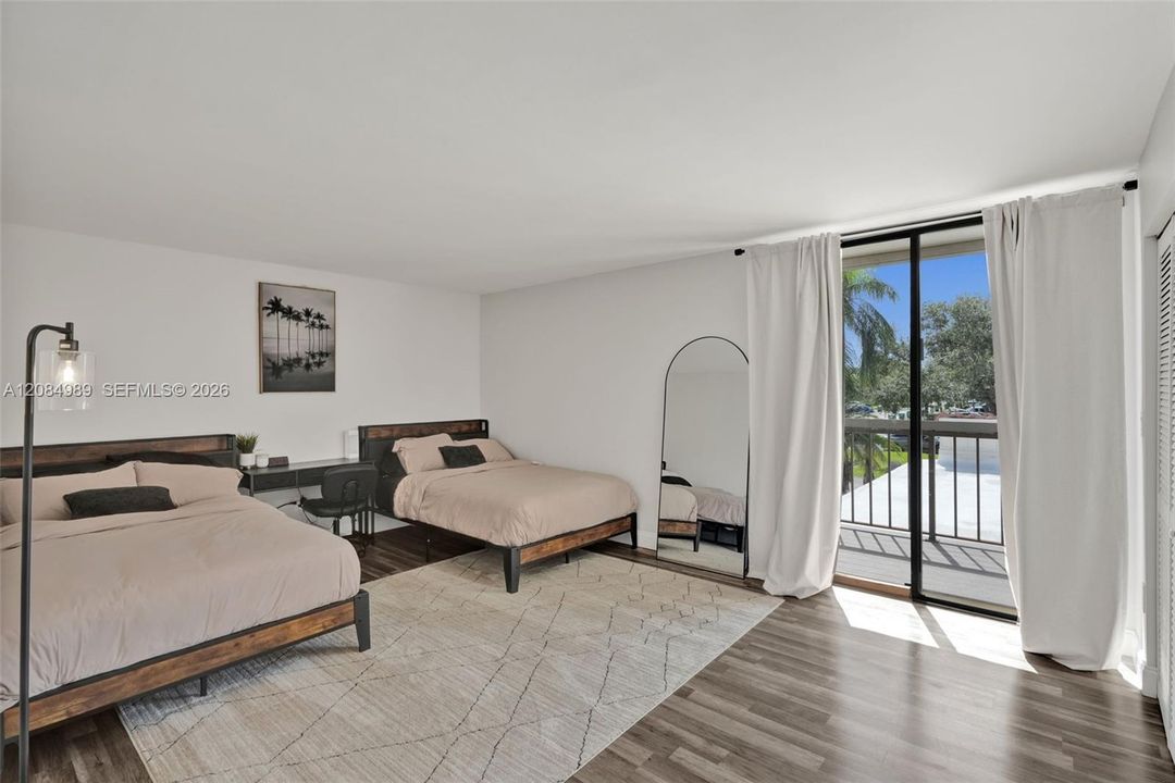 Interior space featuring wood-finish flooring, sliding glass door, and exterior balcony with metal railing