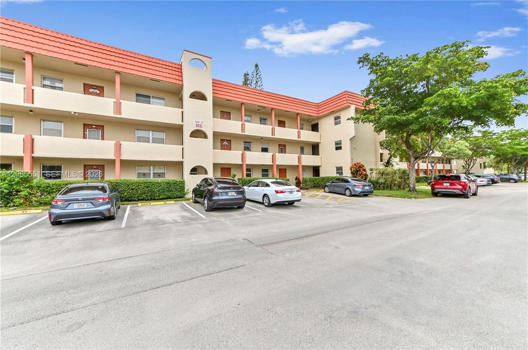 Multi-story exterior featuring a decorative terra cotta roofline, stucco siding, and designated surface parking