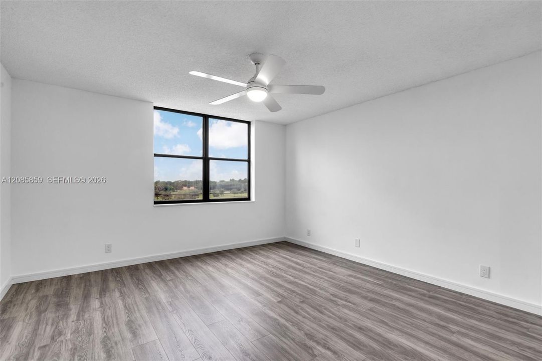 Move-in ready bedroom offering clean wood-look flooring, ceiling fan, and natural light.