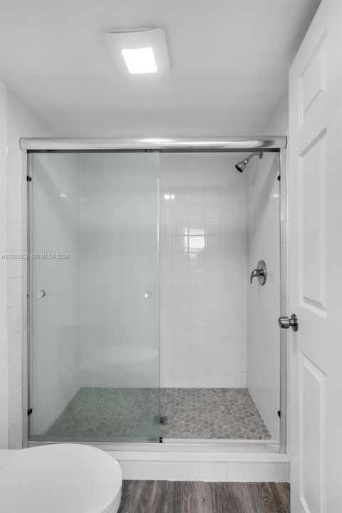 Clean, modern shower design featuring modern glass doors and pristine tiled walls.