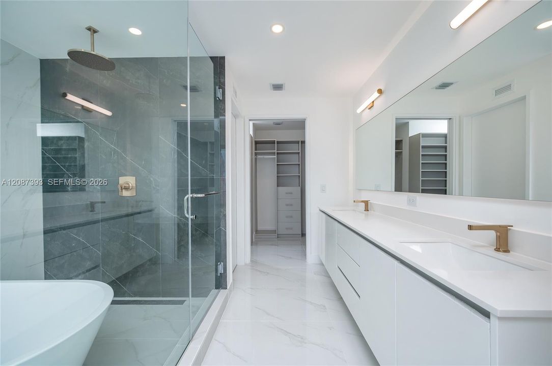Elegant bathroom with lighted mirrors and lamps matching the brass fixtures