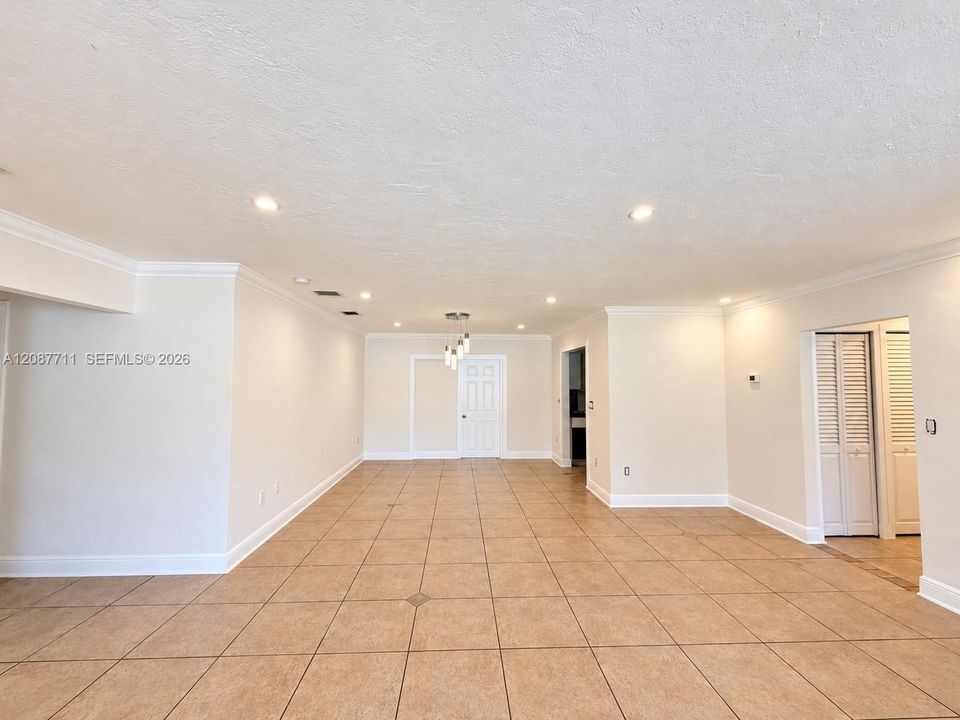 Open-concept interior featuring oversized tile flooring, recessed lighting, crown molding, and louvered closet doors