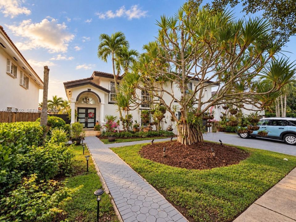 Soft sunrise light warms the elegant arched entrance, framed by lush tropical greenery. A charming garden path leads to the front door, offering a peaceful welcome home.