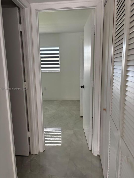 Large-format tile flooring, louvered closet doors, and crisp white interior paint
