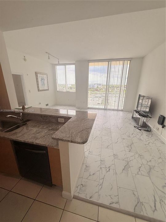 Kitchen featuring stone-finish countertops, stainless steel sink with metal faucet, floor-to-ceiling windows, and tile flooring with a veined pattern