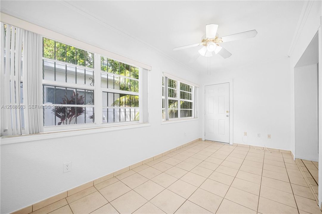 Bright dining room filled with natural light, featuring tiled flooring and a ceiling fan.