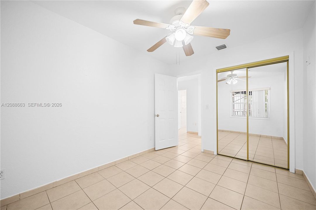 Bright second bedroom featuring ample layout flexibility, bright windows, and mirrored closet storage.