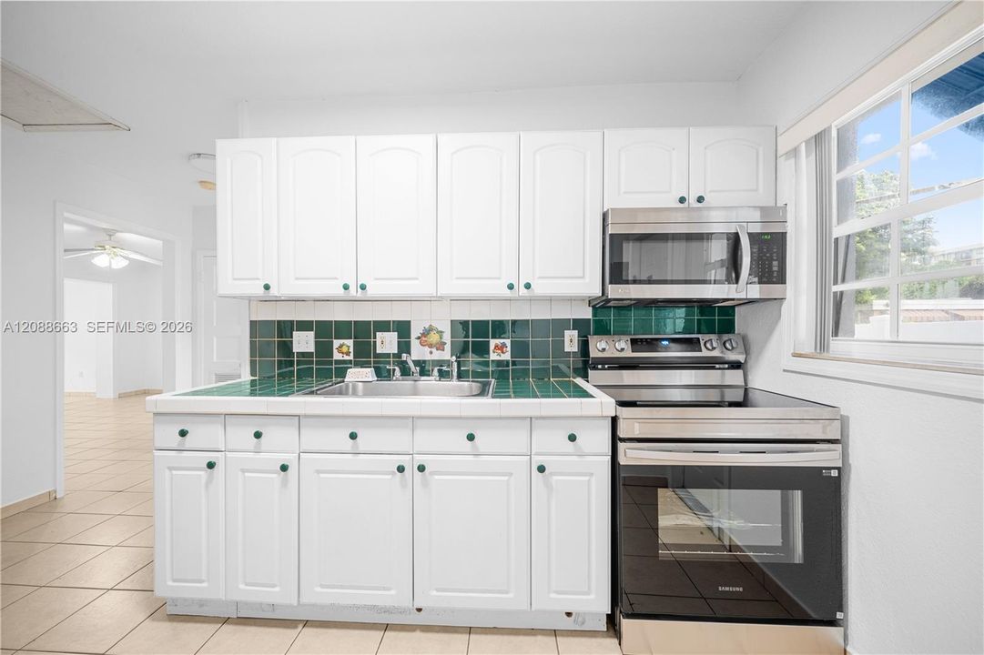 Updated kitchen equipped with white cabinetry, durable countertops, built-in microwave, and stainless steel range.