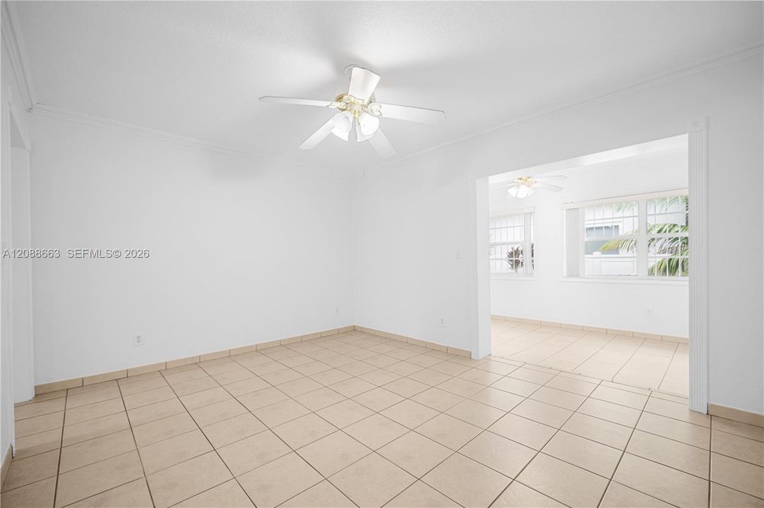 Spacious formal living room filled with natural light, neutral ceramic tile flooring, and central air conditioning with ceiling fan.