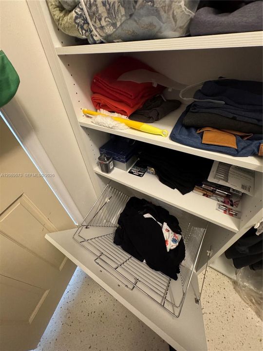 Custom shelves in primary walk-in closet with built-in laundry hamper.