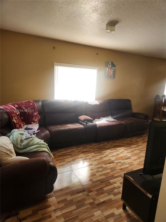 Room interior featuring neutral wall paint, multi-tonal ceramic tile flooring, and a window with horizontal blinds