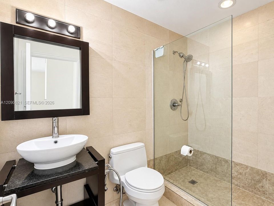 Updated bathroom with glass-enclosed shower, modern vanity, and sleek lighting.