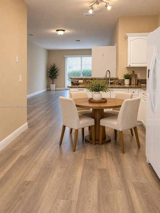 Hard-surface wood-finish flooring throughout, track lighting, ceiling-mounted light fixture, white cabinetry, and a sliding glass door