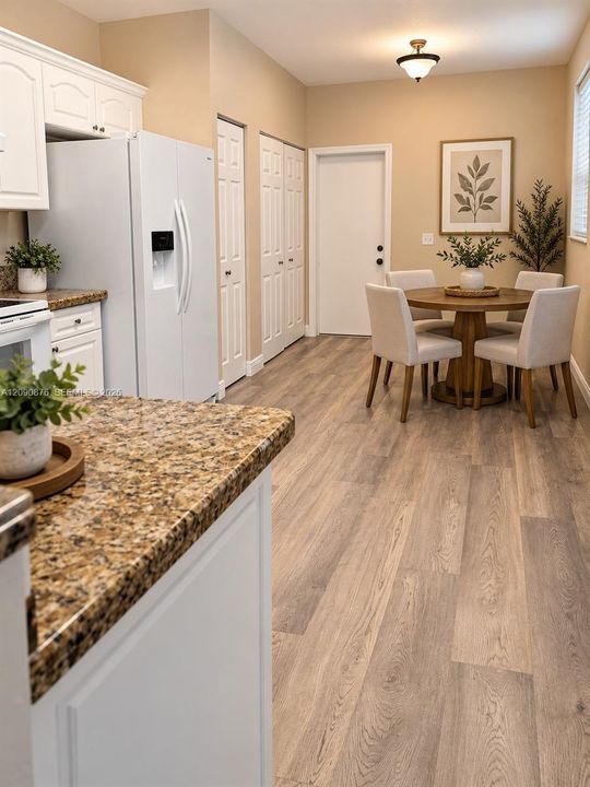 Kitchen featuring white cabinetry, granite countertops, wood-finish flooring, and a dining area with a flush-mount light fixture