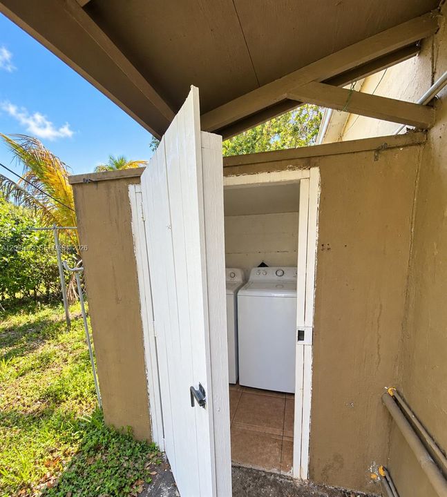 Exterior laundry enclosure featuring a solid-hinged door, tile flooring, and dedicated hookups for a washer and dryer