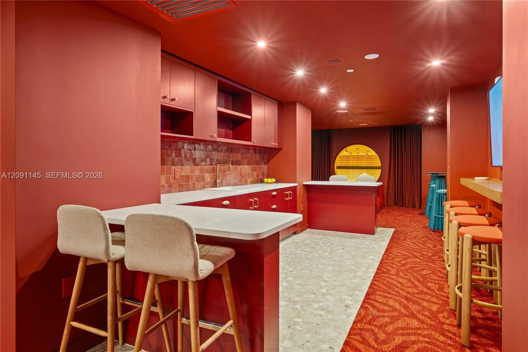 Wet bar featuring built-in cabinetry, solid surface countertops, a tiled backsplash, and recessed lighting