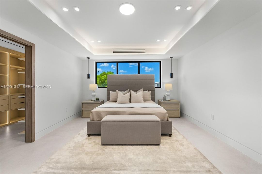 Tray ceiling with recessed lighting, integrated accent lighting, large windows with black frames, and a walk-in closet with built-in storage shelving