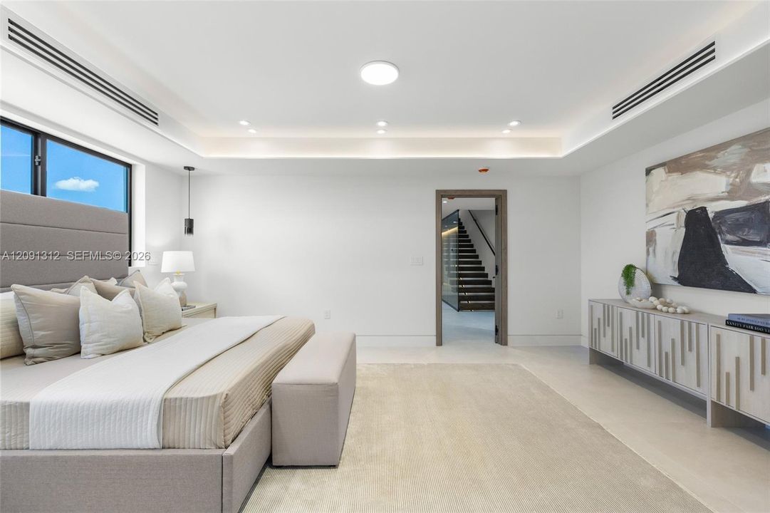 Tray ceiling with integrated lighting, custom built-in cabinetry, and recessed linear HVAC diffusers