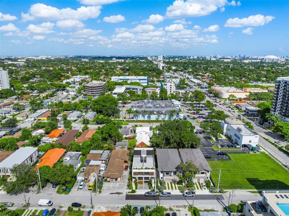 Aerial perspective of a multi-story residence featuring a flat roofline, horizontal facade detailing, and a paved private driveway