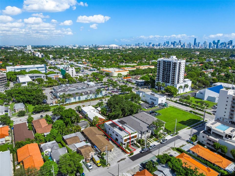 Aerial perspective of a multi-story residence featuring a flat roof with solar panels, a private rooftop deck, and balcony enclosures with horizontal slat privacy screening