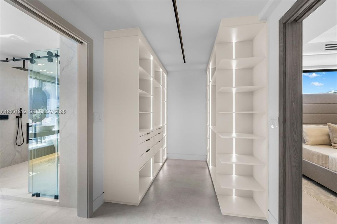 Custom walk-in closet featuring floor-to-ceiling built-in cabinetry, integrated vertical accent lighting, and multi-drawer storage units