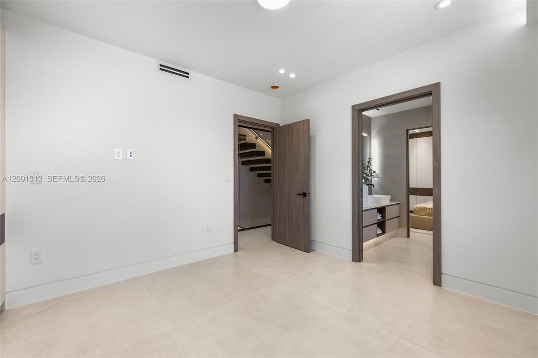 Interior space featuring neutral large-format tile flooring, recessed ceiling lighting, and wood-finish door frames