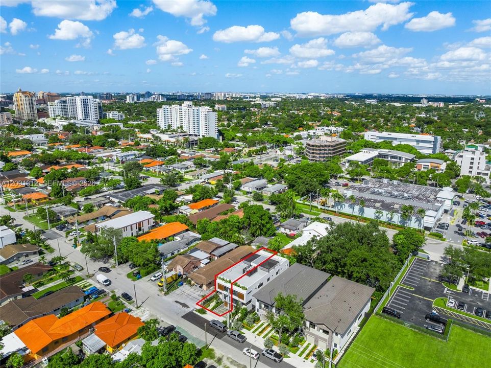 Aerial perspective of a multi-level structure featuring a rooftop terrace, clean-lined modern exterior, integrated landscaping, and paved driveway