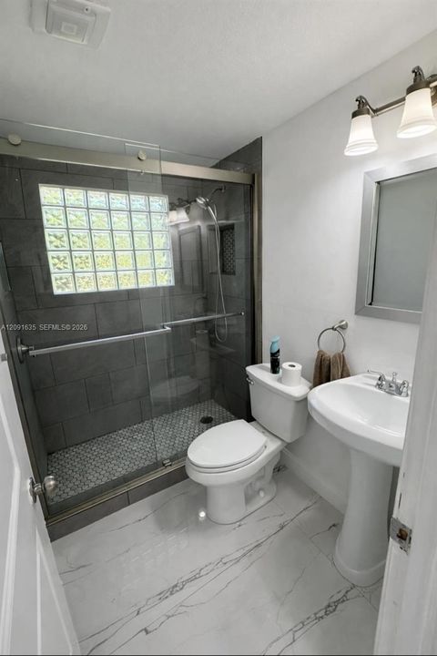 Fully updated bathroom featuring contemporary fixtures and a sleek frameless glass shower enclosure.
