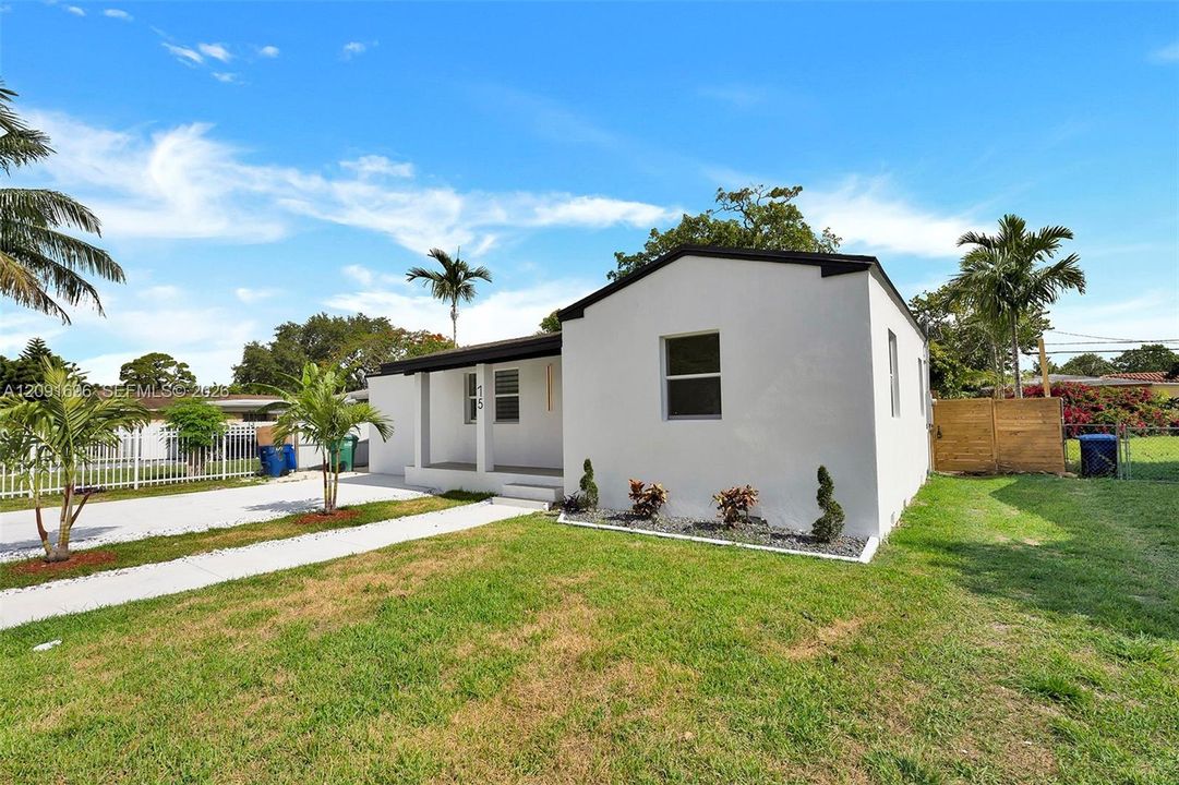 Single-story residence featuring a smooth stucco exterior, covered front porch, concrete driveway, and wooden perimeter fencing