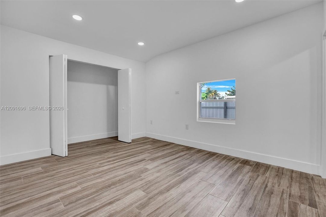 Room featuring wood-finish flooring, recessed lighting, and a closet with bifold doors