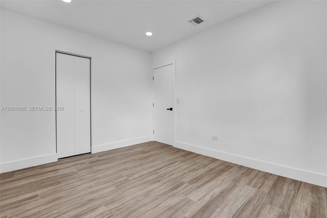 Interior space featuring wood-finish flooring, recessed lighting, and a bifold closet door with matte black hardware