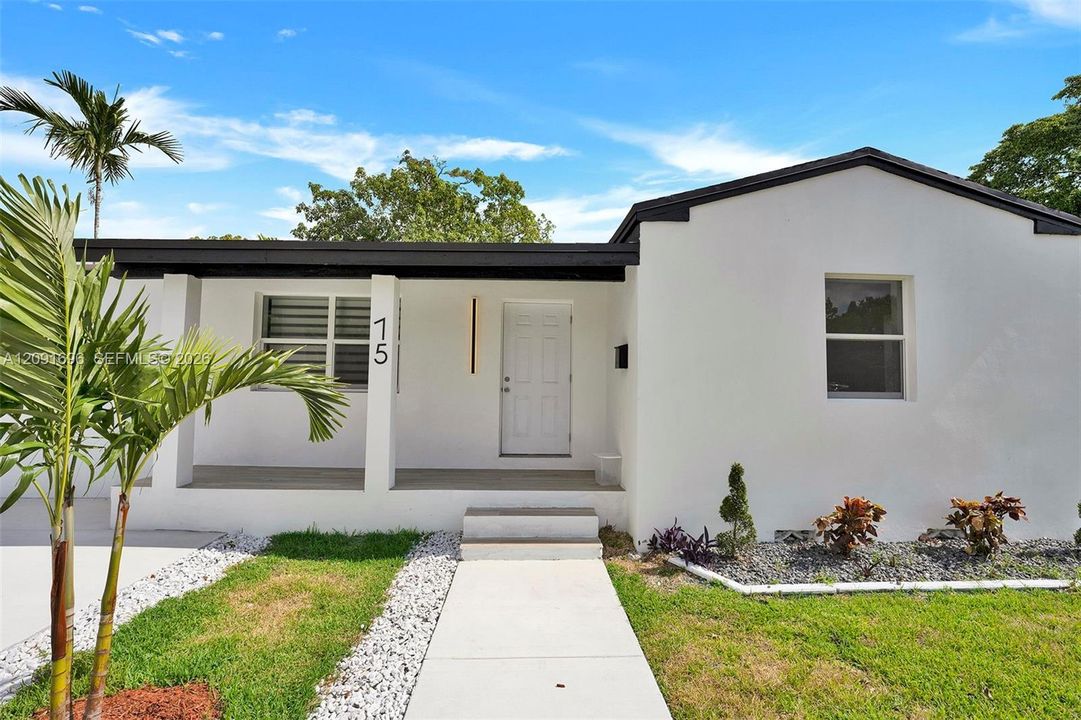Single-story exterior featuring white stucco siding, a covered entryway with square columns, a concrete walkway, and dark trim accents
