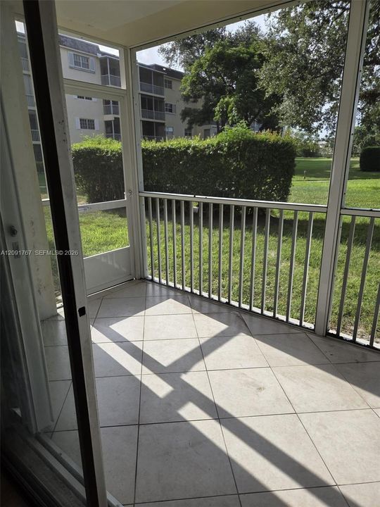 Screened-in porch featuring tile flooring, metal frame enclosures, and a metal railing