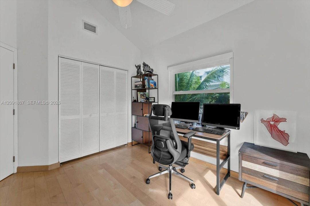 Vaulted ceilings, wood-finish flooring, and white louvered-door closet featuring a ceiling fan and natural lighting
