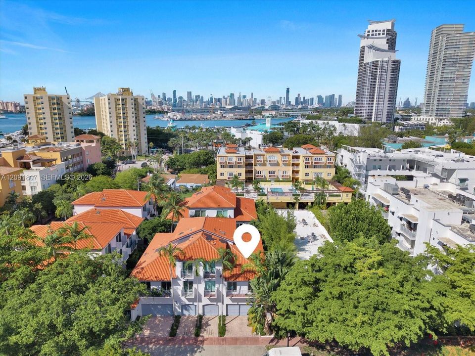 Multi-level building featuring a terracotta tile roof, white stucco facade, private garage bays, and mature palm trees