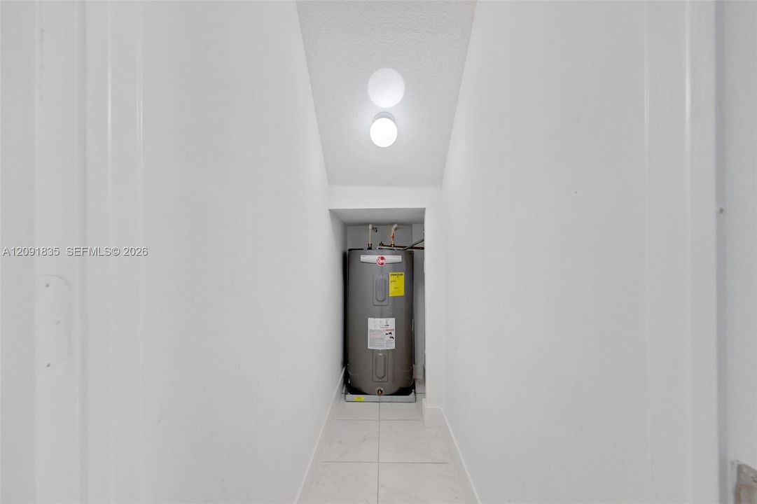 water heater, white tile flooring, and a ceiling-mounted light fixture