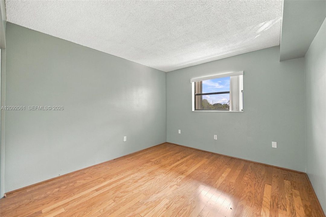 Interior room featuring wood-finish flooring, light-toned wall paint, and a single-pane window with a horizontal blind