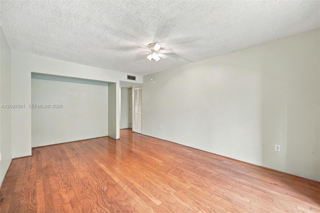 Spacious interior featuring wood-finish flooring, a ceiling fan with integrated lighting, and neutral wall paint
