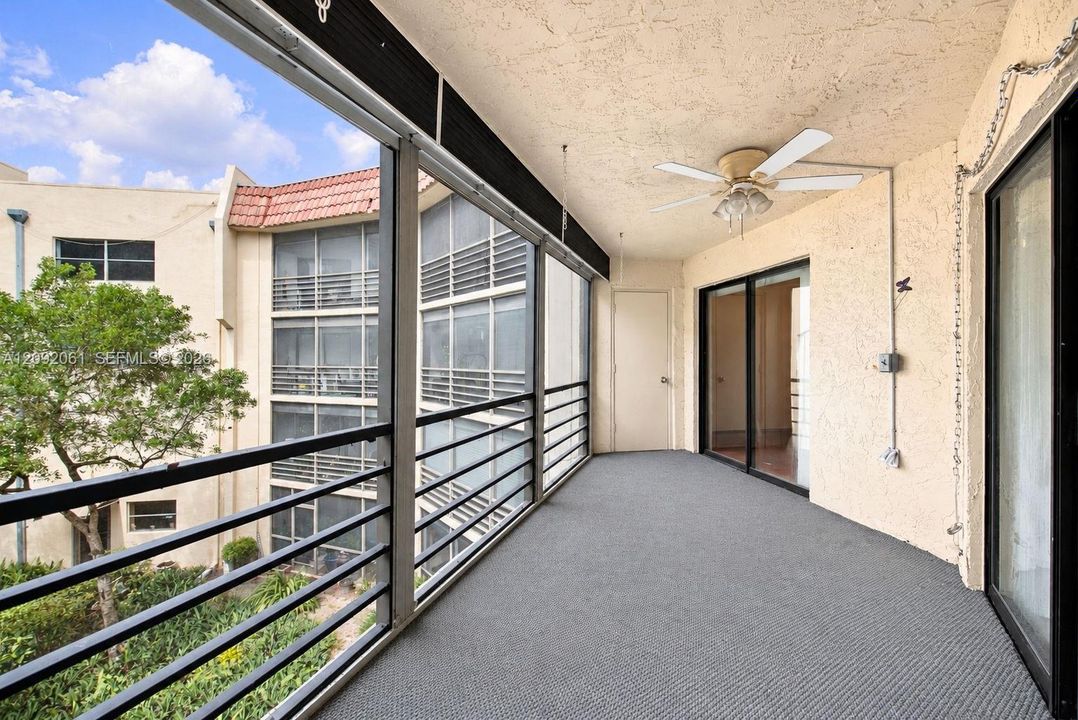 Screened balcony featuring metal railings, textured wall finish, ceiling fan, and carpeted flooring