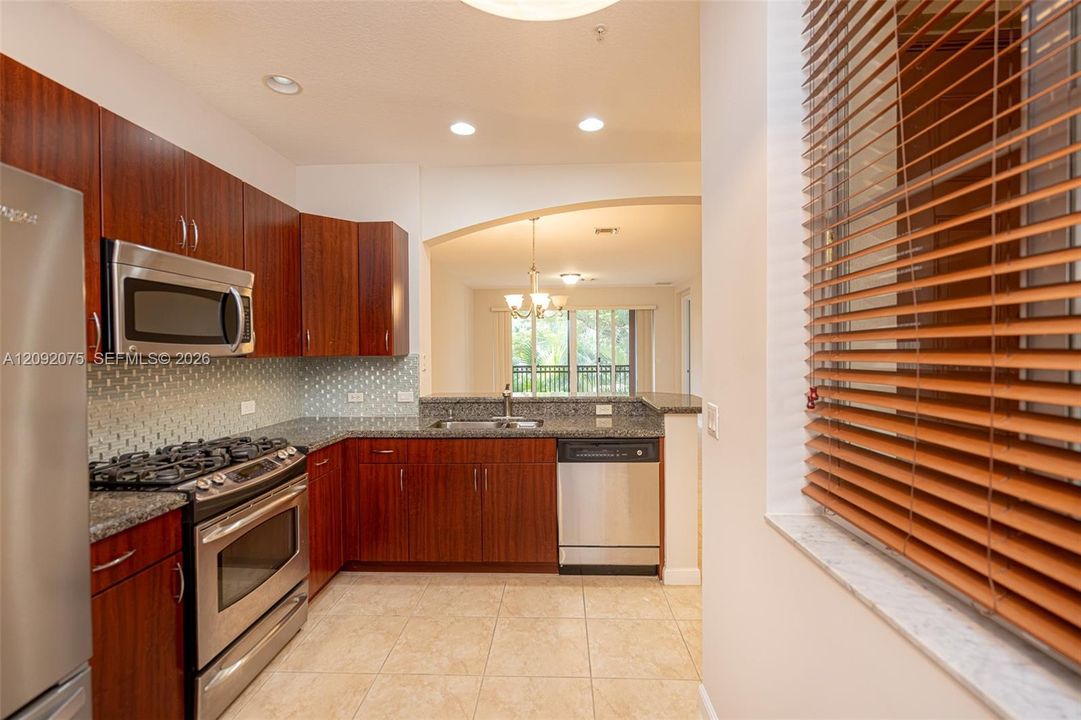 Full-sized kitchen with stainless steel appliances, granite countertops, and tile flooring