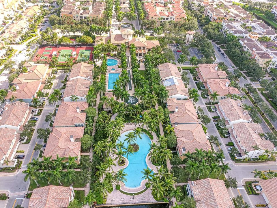 Community featuring multiple swimming pools, tennis courts, and mature landscaping with palm trees